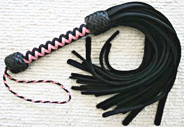 A pink and black zig zag handle on a bison flogger.